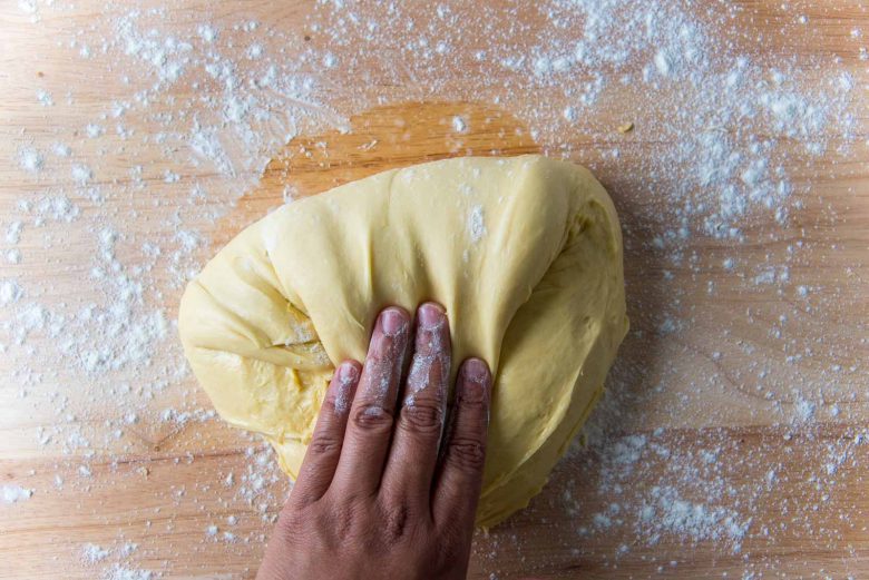 Folding another end of the brioche dough by hand towards the middle.