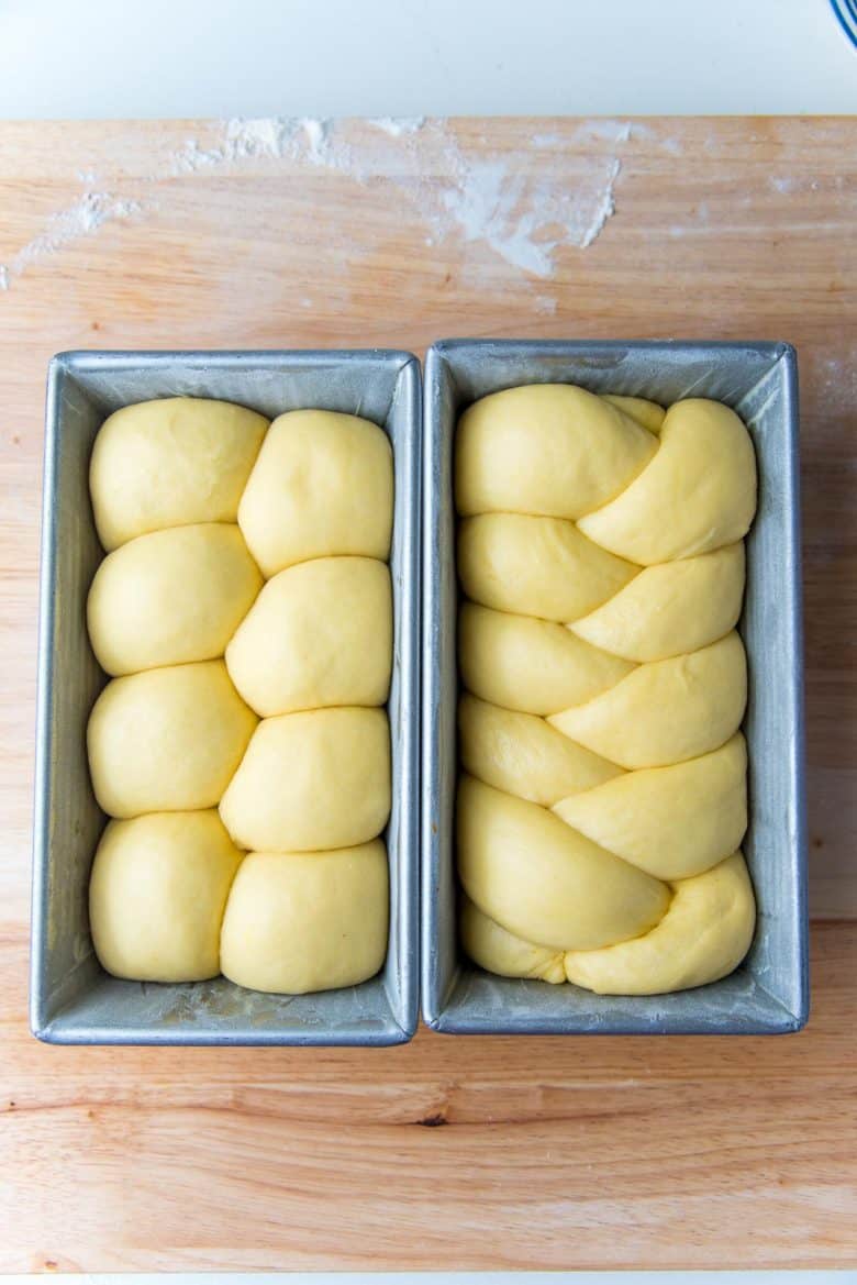 Proofed nantaise and braided brioche loaves in two loaf pans.