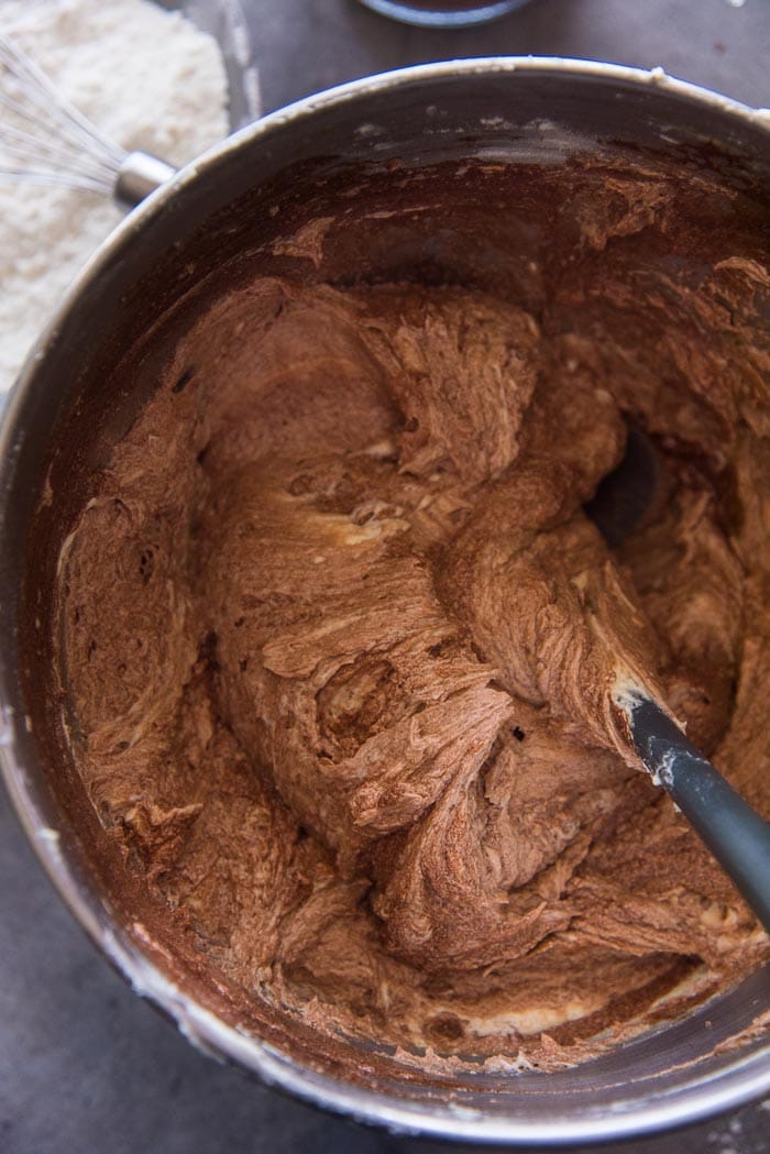 Halfway through the process of folding in the flour and chocolate milk. The batter is folded in using a spatula.