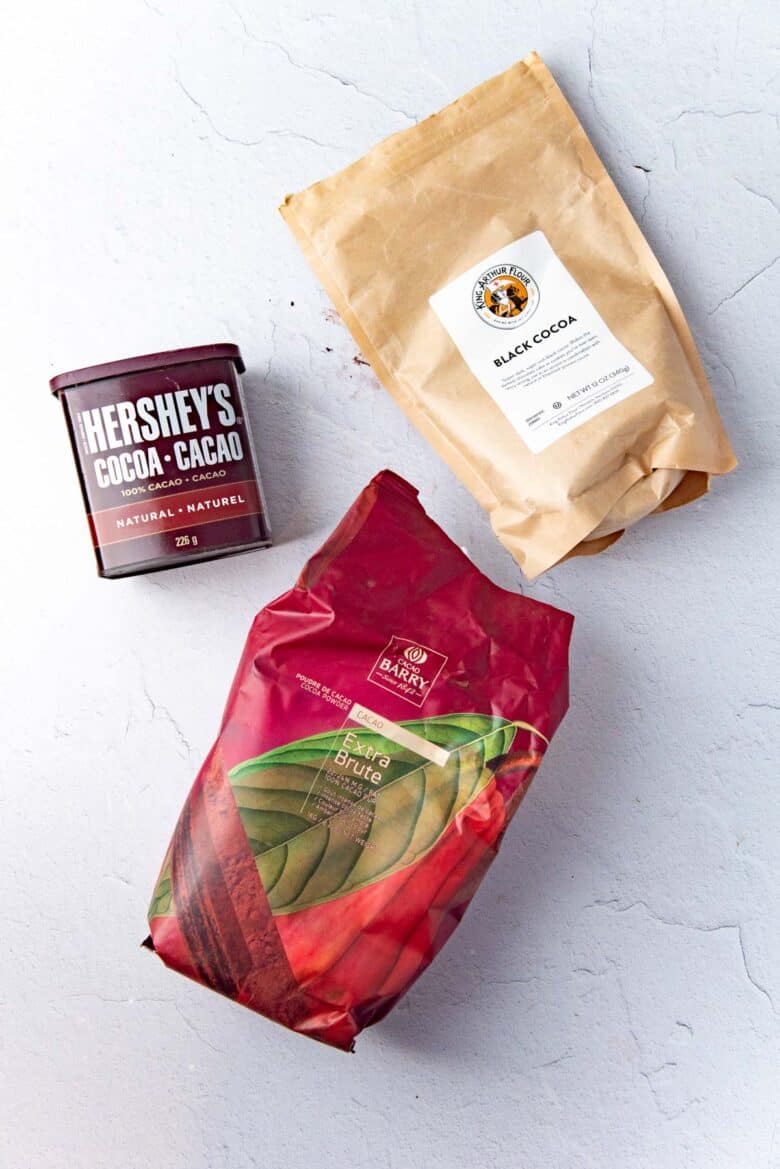 3 types of cocoa powder packages laid on top of a whitish grey background.