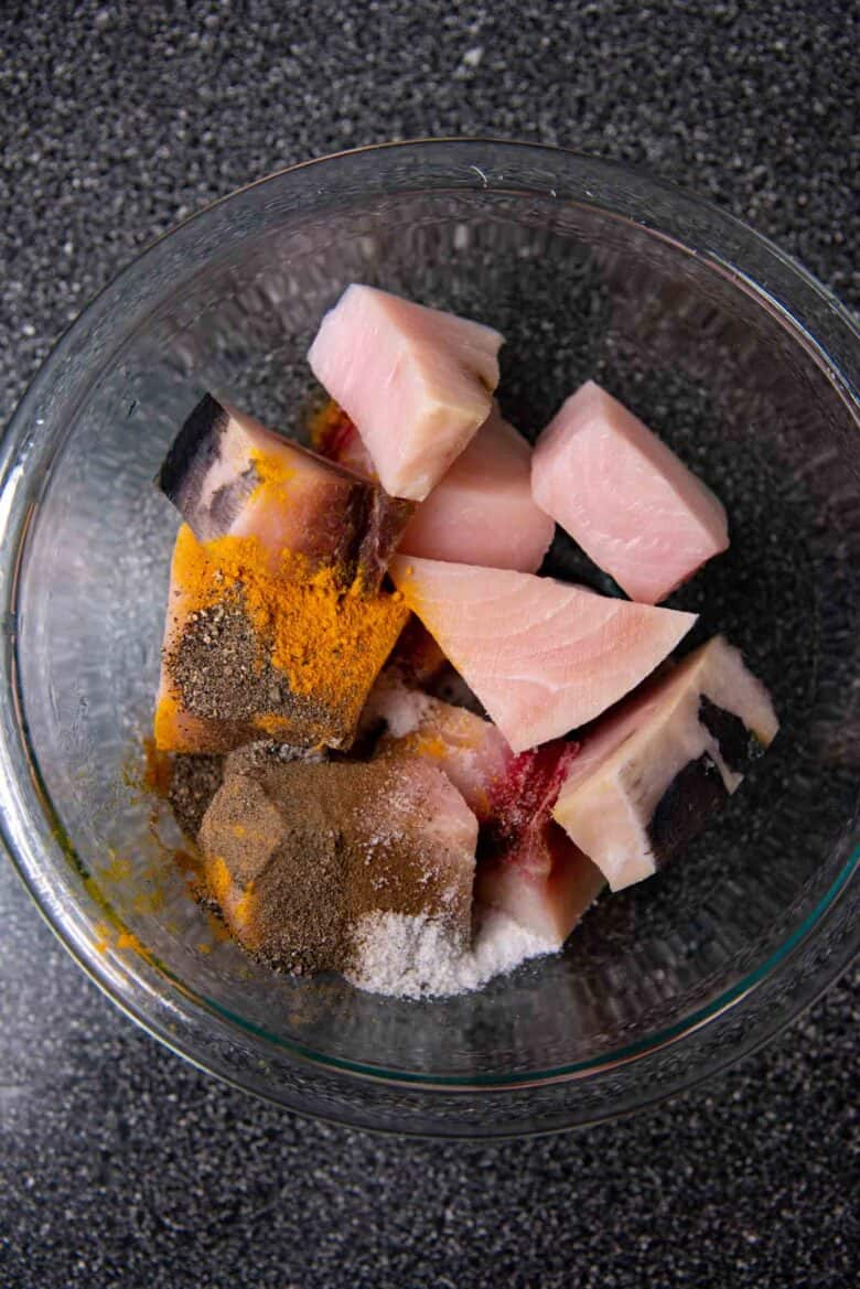 Swordfish cut into pieces in a bowl with the spices