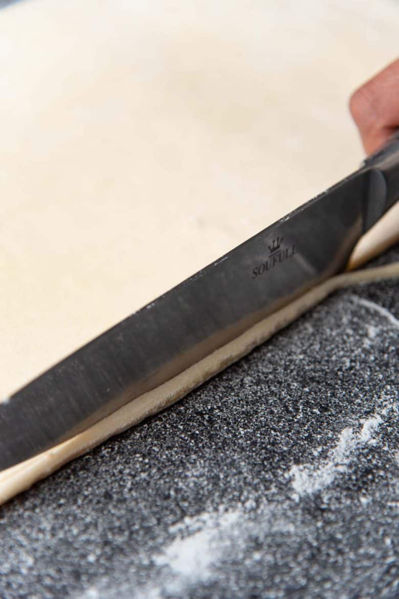 Trimming the edges of the croissant dough with a knife