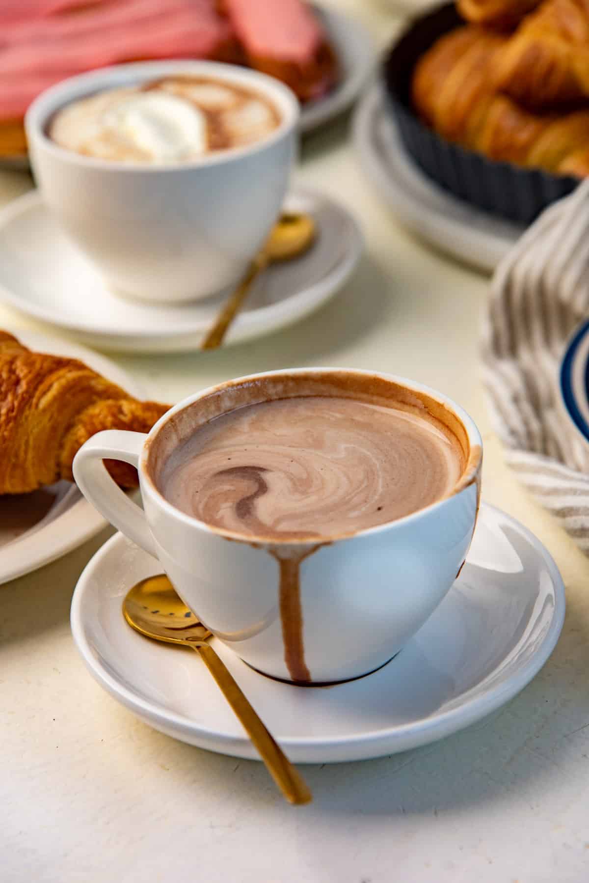 A white cup full of thick French hot chocolate, placed on top of a saucer.