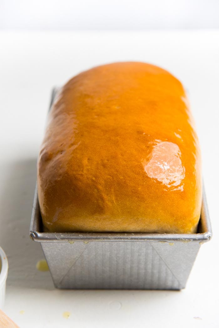 A perfectly baked, golden homemade bread loaf while still in the pan.