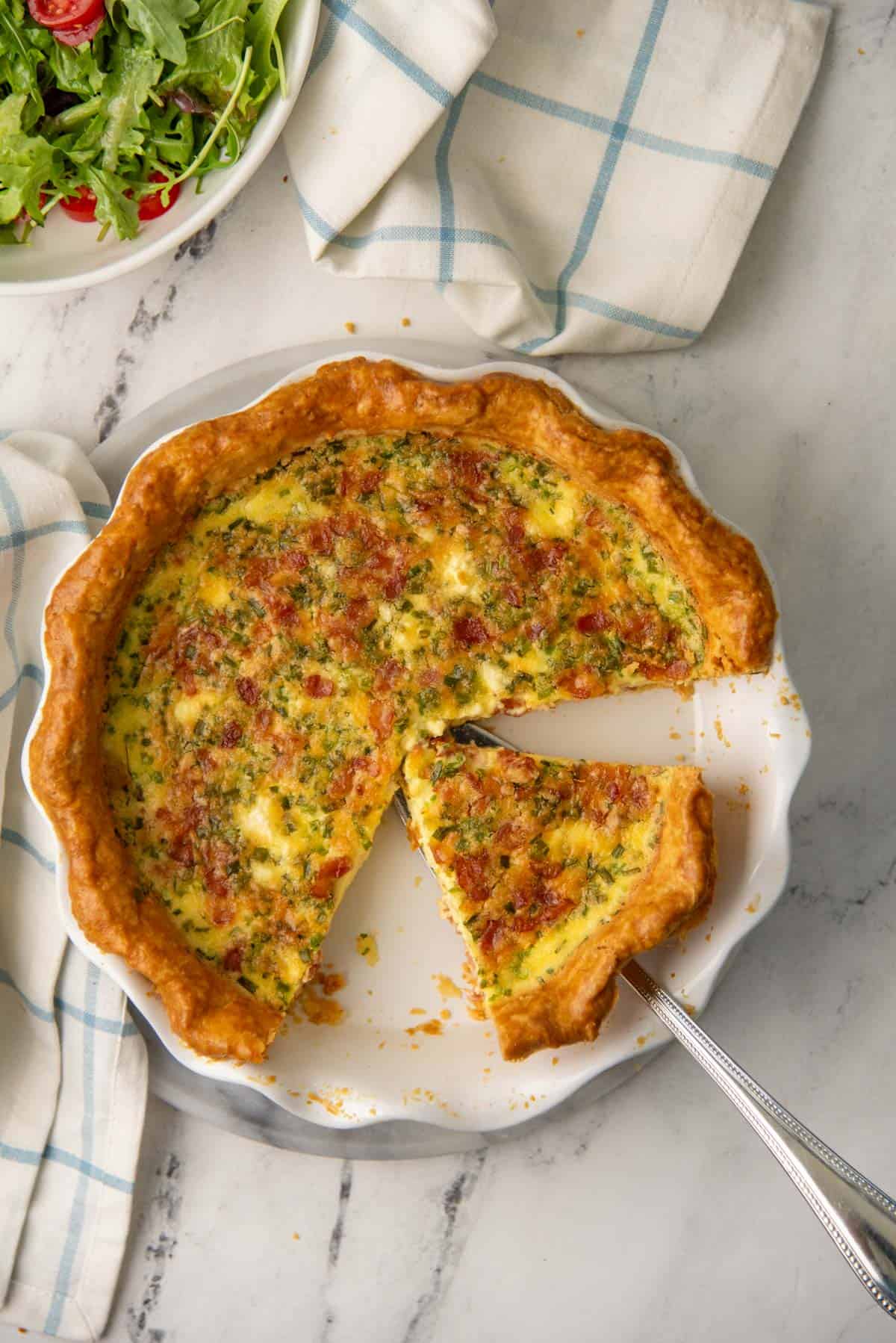 Overhead view of quiche lorraine in dish, with a slice taken out.