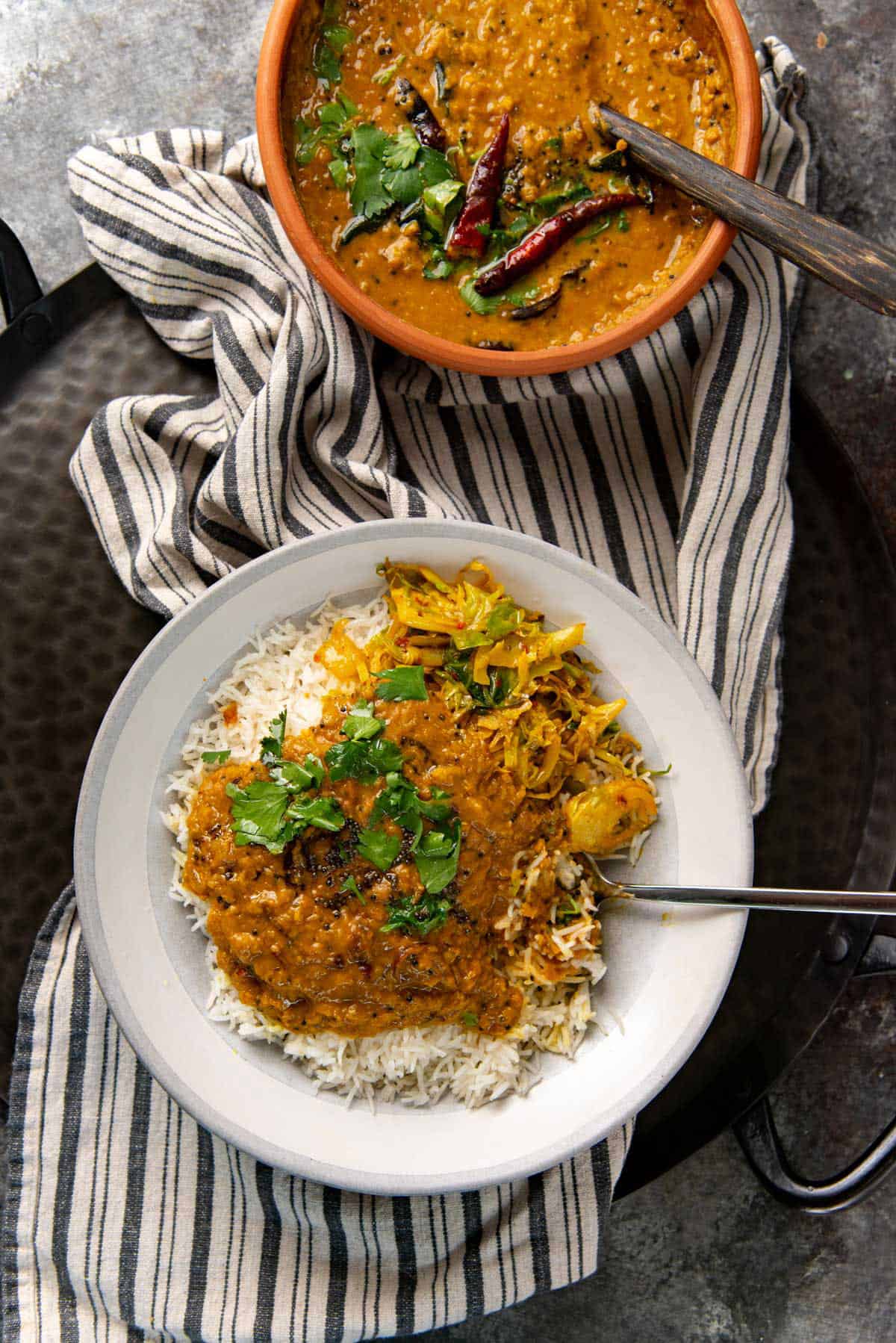 Sri Lankan dhal curry served with cooked white rice in a gray serving plate.