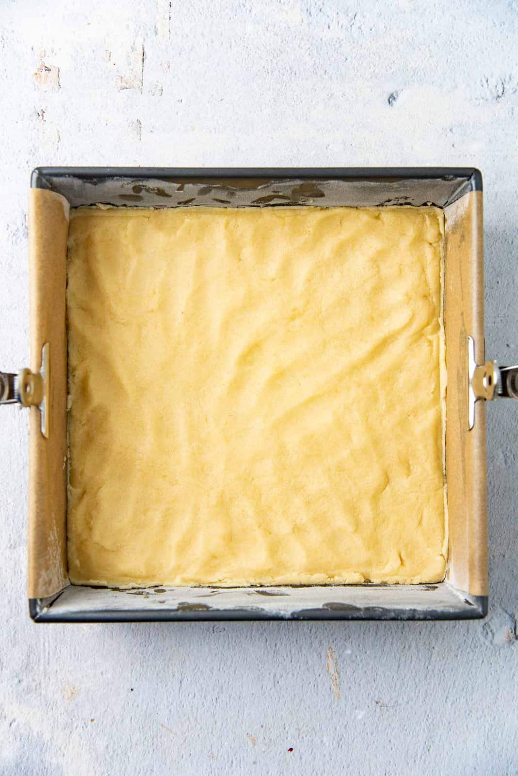 The shortbread dough pressed into the bottom of the baking pan