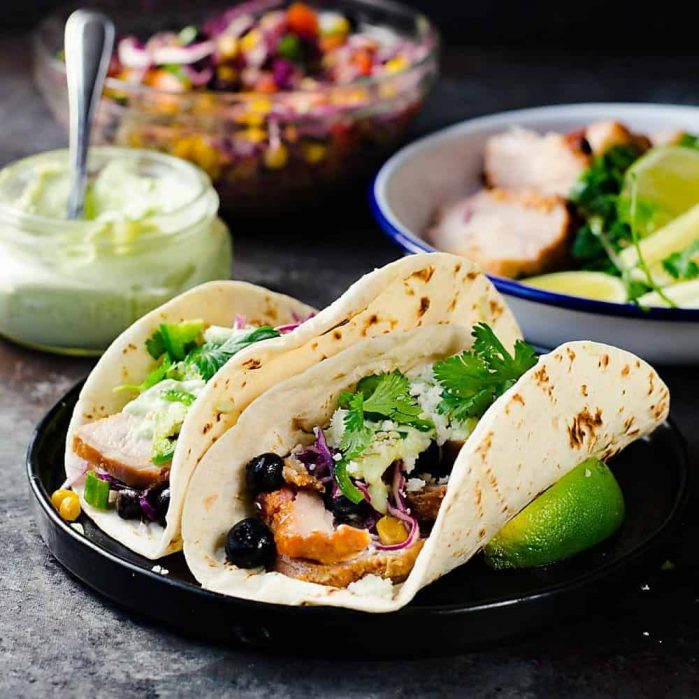 Roasted Pork Tacos  with blueberry coleslaw - Tacos with tender pieces of roasted applewood smoked bacon Pork loin, and topped witha a fresh and light blueberry rainbow coleslaw with an almond honey mustard dressing (no mayonnaise), and an Jalapeno avocado crema. A meal that's ready in 30 minutes with some life saving shortcuts!