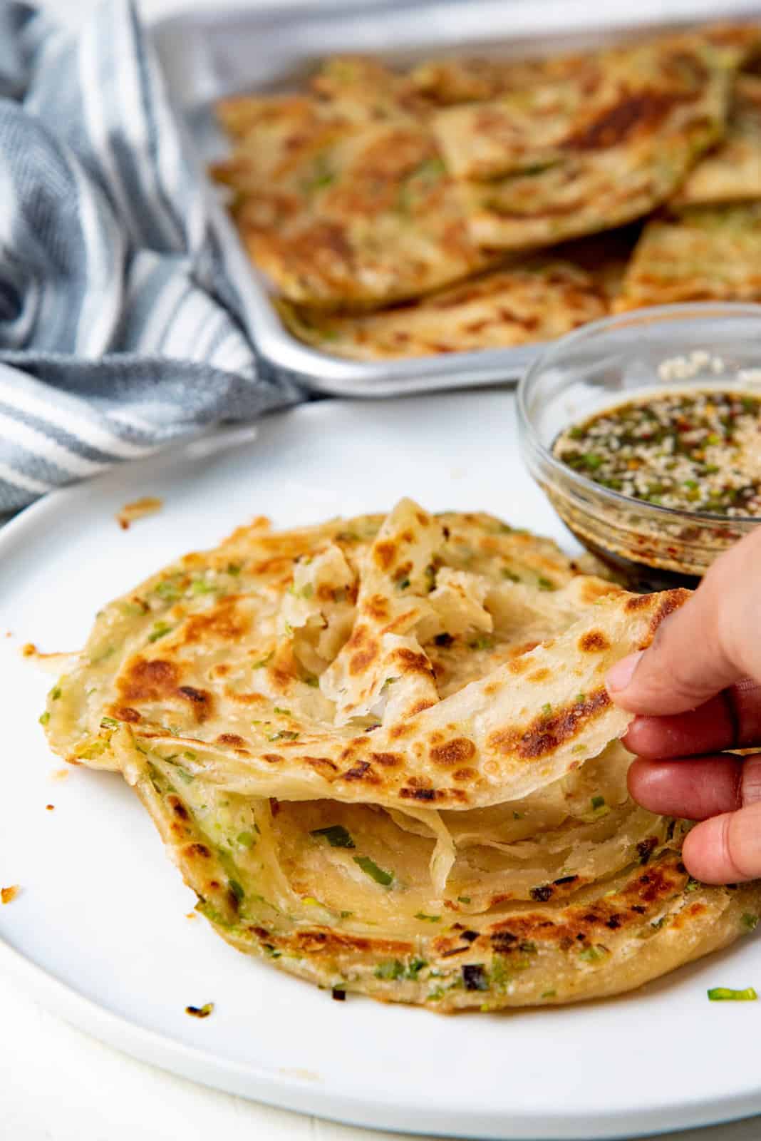 A hand pulling on the flat bread, showing the layers present in the flat bread.