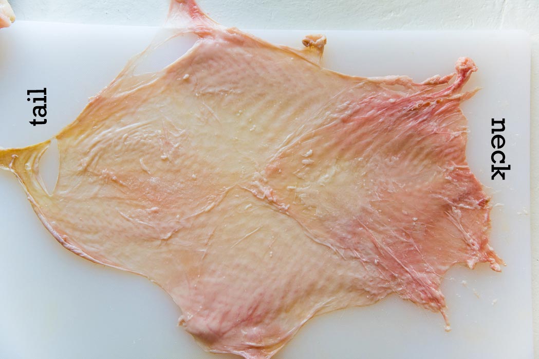 Step 5 is to clean the skin by scraping off the fat. Stretch it out on the cutting board to make it as large as possible.